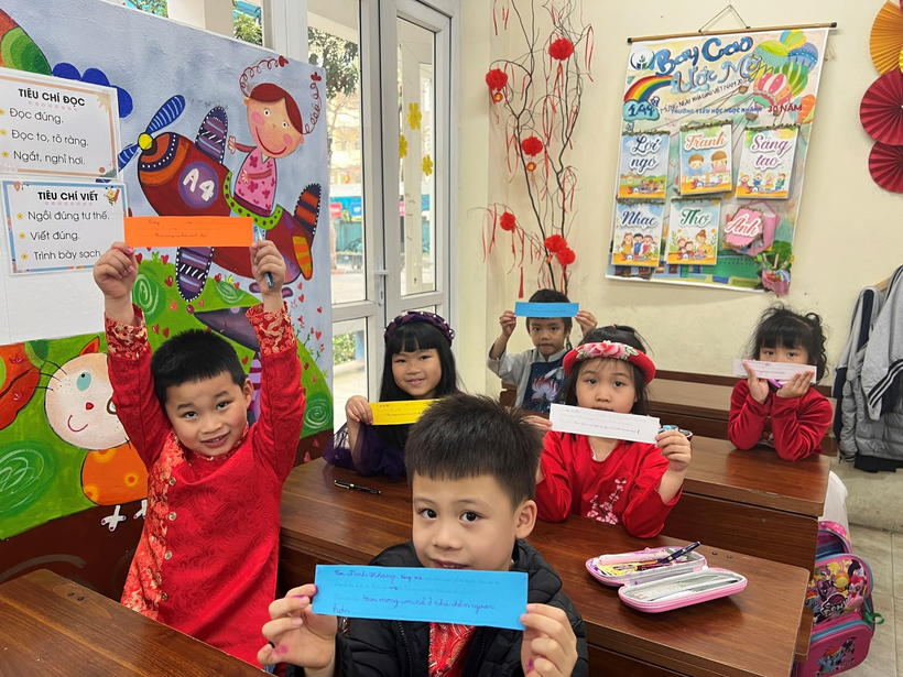 A group of children in a classroom holding up signs

Description automatically generated