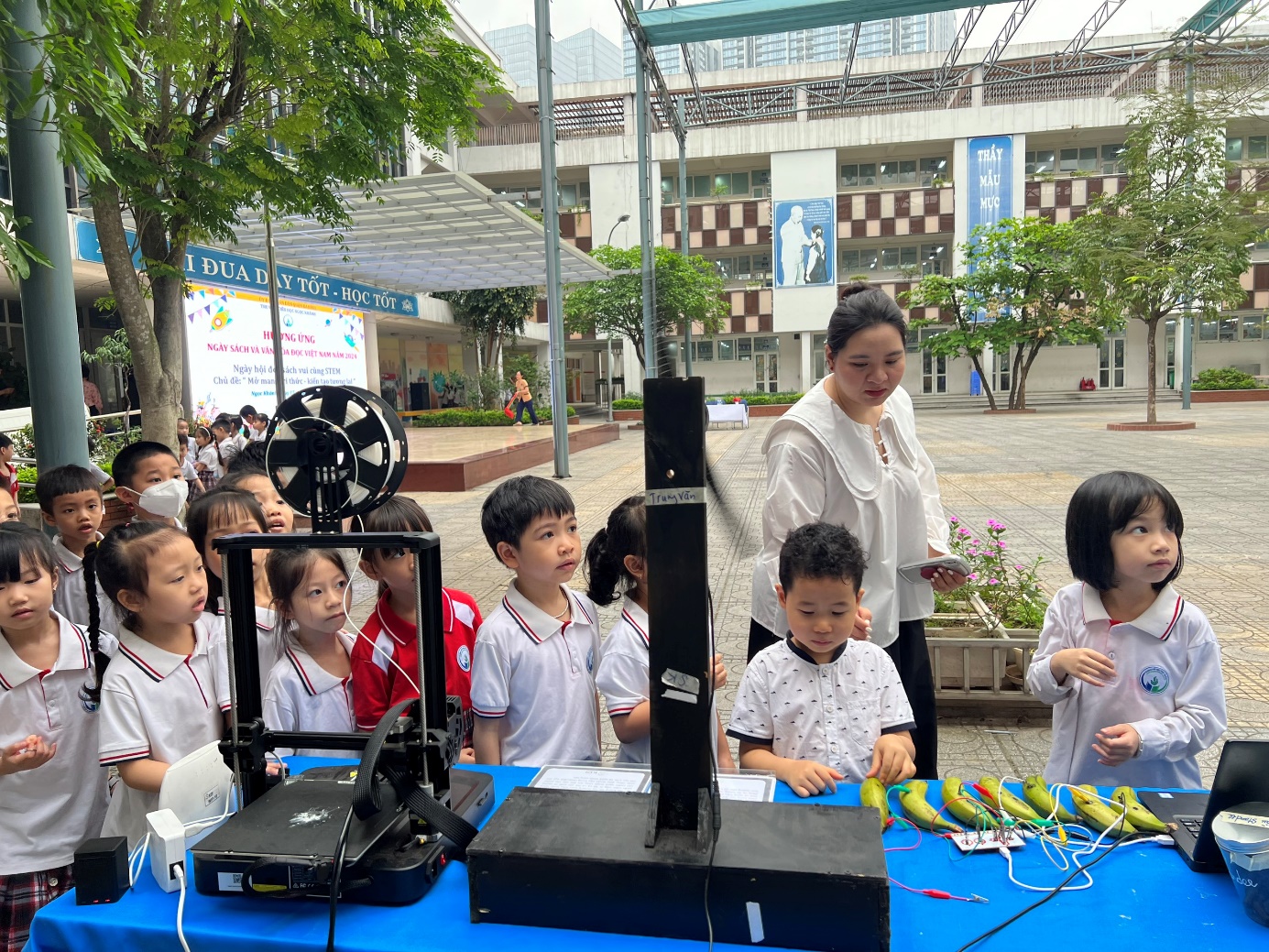 A group of children in front of a table with a machine

Description automatically generated